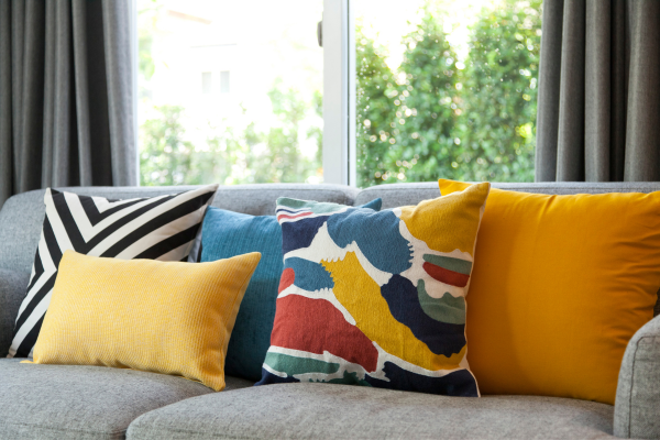 An assortment of throw pillows on a sofa featuring various pattern scales, with large-scale and small-scale designs, demonstrating how to mix and match pillows on a sofa by varying pattern sizes.