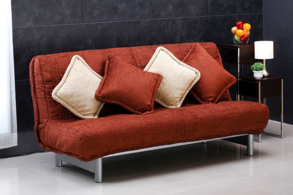 A sofa adorned with throw pillows of different sizes and textures, including velvet, knit wool, and faux fur, illustrating how to mix and match pillows on a sofa by varying size and texture